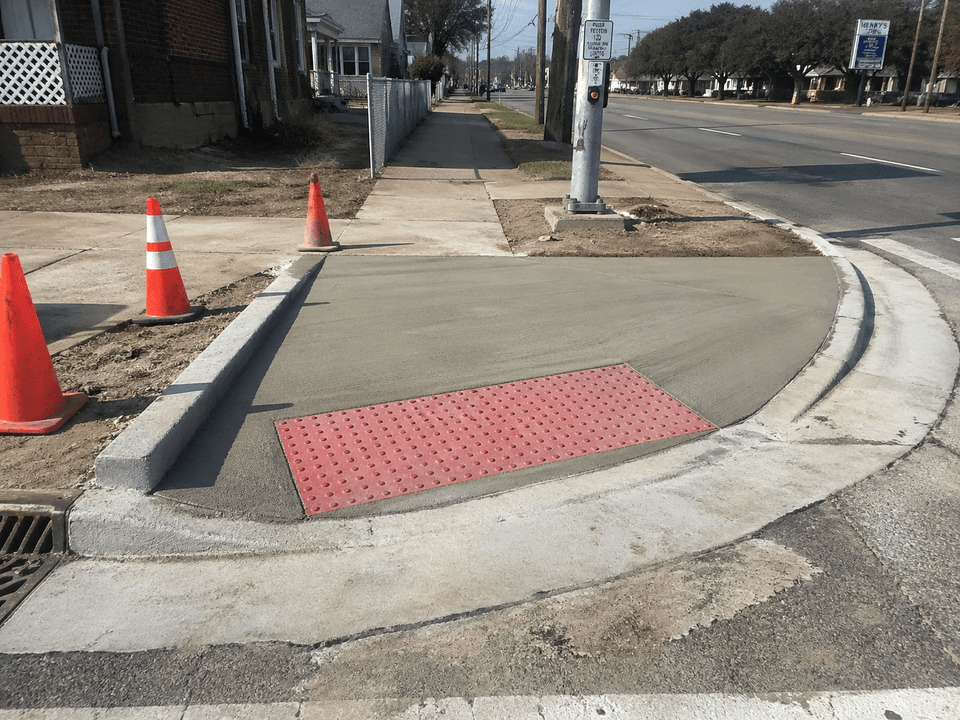 Completed ADA-compliant pedestrian ramp with red truncated dome panel on a Shreveport corner